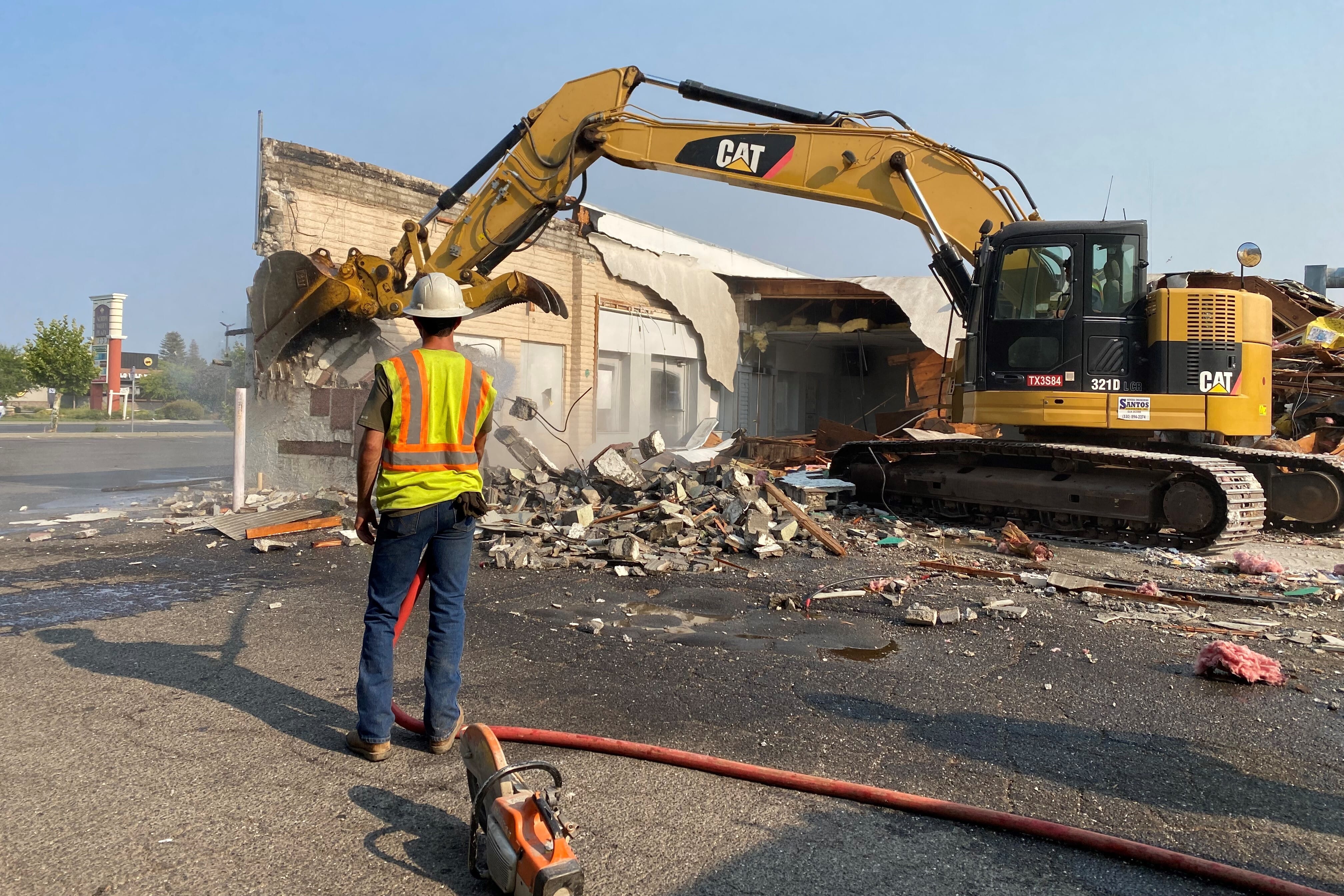 Man in reflective vest observing a demolition of a building